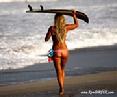 Image of Jamilah Star heading to the waves with surf board on head